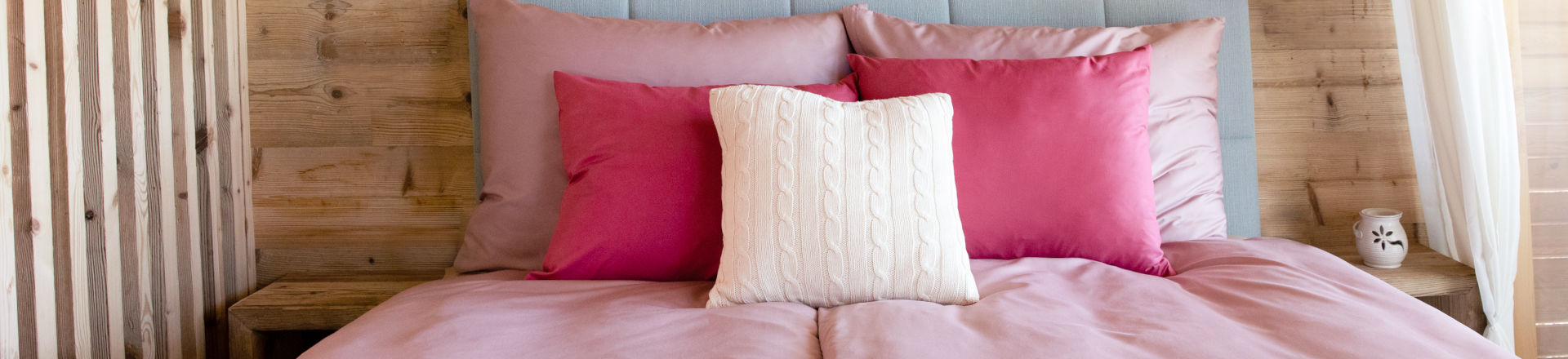 Jak vypadá ustlaná postel s produkty od SCANquilt, růžové povlečení a pletené povlaky.